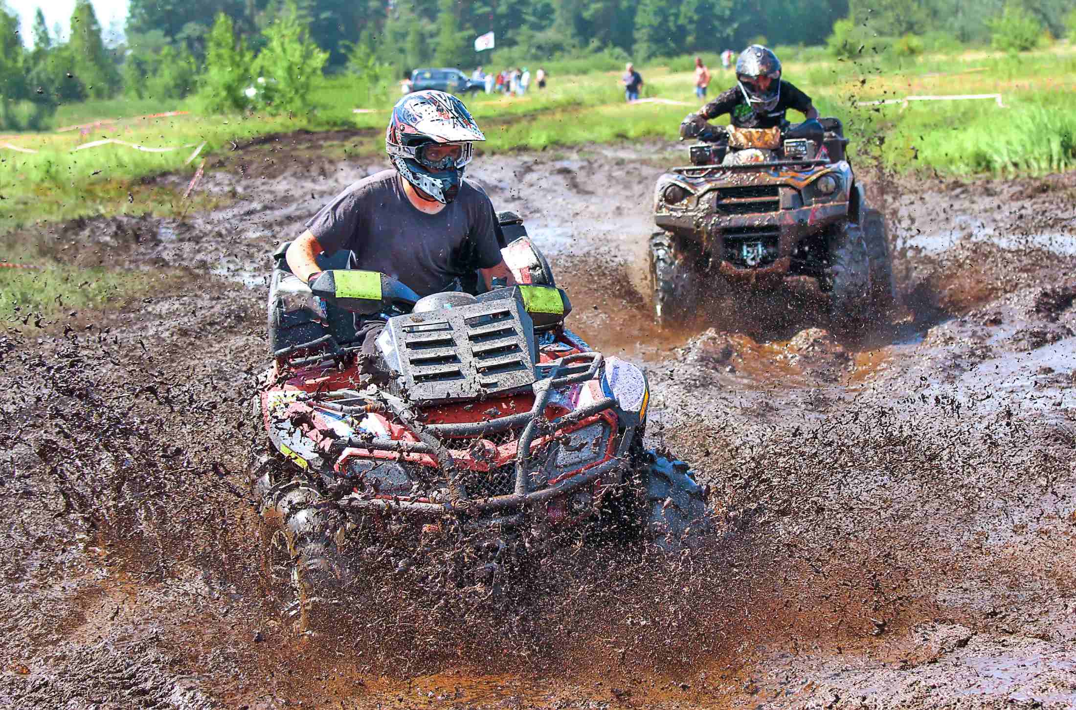 Two dirt bikers running vehicle in mud